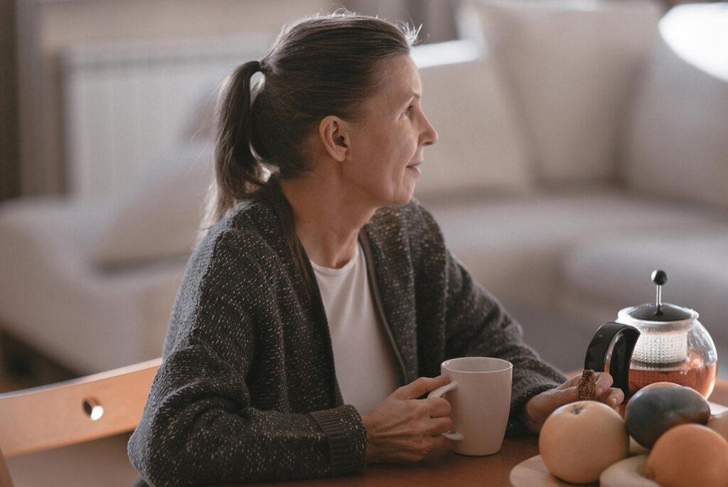 Kvinde sidder med sin kop kaffe i sin sofa