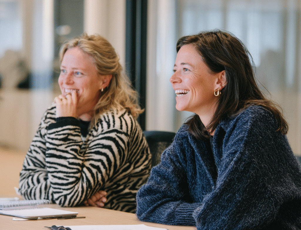 To unge kvinder, der sidder ved et bord og smiler